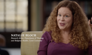 Video still image of Bloch sitting in a chair, speaking